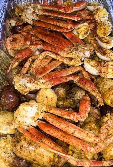 A tray of steamed snow crab legs, shrimp, corn and potatoes seasoned with Old Bay